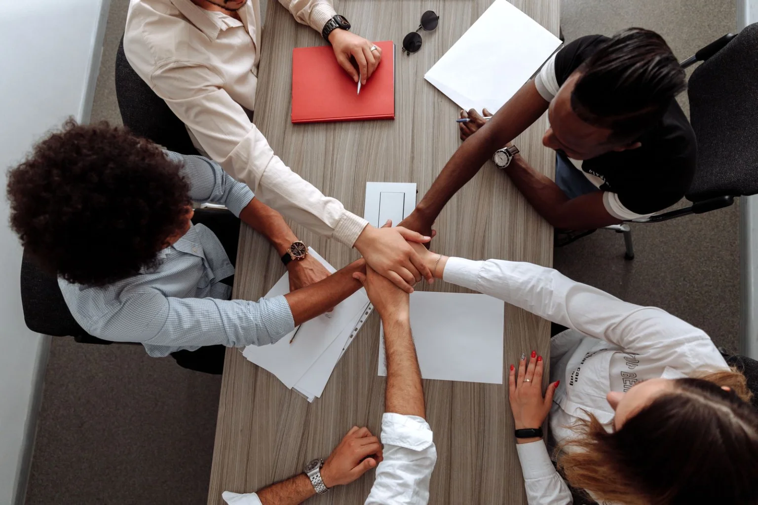 Team members joining hands over a desk in collaboration