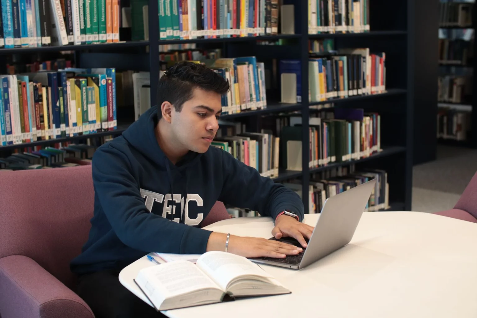MSN student studying with a laptop and textbook in a library